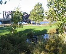 View of the bridge and the wheel commemorating the industrial activities of the site.; Village of Saint-Louis-de-Kent