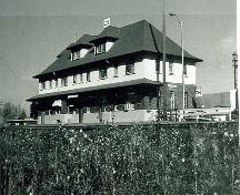 Vue en angle de la Gare ferroviaire Canadien Pacifique, qui montre les façades du devant et du côté.; Smithers, 1980.