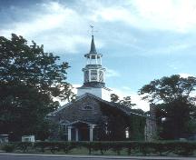 View of the exterior of St. Stephen's Anglican Church, showing the three-tiered steeple and the main entrance with its double doors and semi-circular glass transom, 1992.; Parks Canada / Parcs Canada, 1992.