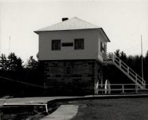 View of the Blockhouse, showing the square, two-storey massing with pyramidal roof, 1989.; Agence Parcs Canada / Parks Canada Agency, 1989.