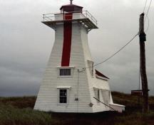 General view of the Back Range Light Tower, showing the square, tapered medium-height tower smoothly, joined to the tapered sides of a one-storey structure with a shingled gable roof, 1986.; Department of Transport / Ministère des Transports, 1986.