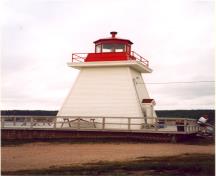 Side view of the Coastal Lighthouse, showing the metal railing at the gallery level and the octagonal metal lantern, 2000.; Department of Fisheries and Oceans / Ministère des Pêches et des Océans, 2000.