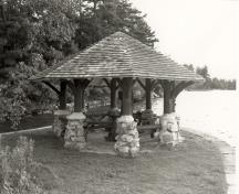 View of the Gazebo of the Batterman's Point Complex, showing the octagonal, shingled roof, rubble-stone piers, and peeled-log posts, 1992.; Parks Canada Agency / Agence Parcs Canada / Historica Resources Ltd., 1992.