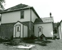 Rear view of the Defensible Lockmaster's House, showing the enclosed east porch and the summer kitchen, 1989.; Parks Canada Agency / Agence Parcs Canada, Couture, 1989.