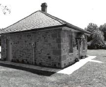Vue en angle de la résidence fortifiée du maître-éclusier, qui montre le toit en croupe et la charpente d’origine du toit et la cheminée, 1989.; Parks Canada Agency / Agence Parcs Canada, Couture, 1989.