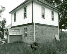 Corner view of the Defensible Lockmaster's House, showing the frame second-floor clad in clapboard, 1989.; Parks Canada Agency / Agence Parcs Canada, Couture, 1989.