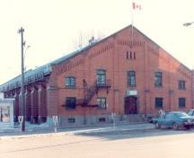 Front elevation of the Armoury in Pembroke, showing its low-pitch roof with corbelled brickwork at the gable end, 1992.; Department of National Defence / Ministère de la Défense nationale, 1992.