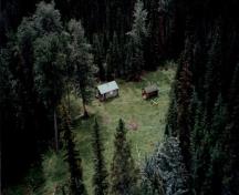 Aerial view of Middle Forks Warden Patrol Cabin, showing the cabin, the clearing, adjacent shed, and the surrounding forest, 1997.; Parks Canada Agency / Agence Parcs Canada, 1997.