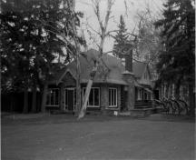 General view of the Golf Clubhouse, showing the peeled log construction walls and extensive stone detailing, 1986.; Parks Canada Agency / Agence Parcs Canada, Mills, 1986.