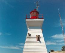 Vue générale du Phare, qui montre la volumétrie sur deux niveaux en pyramide tronquée à base carrée de sa tour courte avec une corniche évasée, 1990.; Canadian Coast Guard / Garde côtière canadienne, 1990.