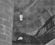 Interior view of the Sargeants Mess / Jebbs Redoubt, Building 13, showing the limestone pier on the left supporting the vault which fans out from it and the entrance to the stairs to the roof, 1991.; Parks Canada Agency / Agence Parcs Canada, R. Godspeed, 1991.