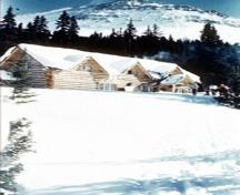 Vue générale de l'Auberge-de-Ski-Skoki montrant sa configuration simple, et sa construction horizontale en billes d'épinette locale non trusquinées et jointes par des assemblages en queue d'aronde ou en sabot, 1959.; Parks Canada Agency / Agence Parcs Canada, 1959