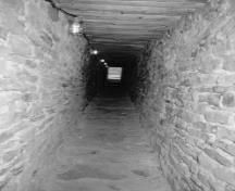 Vue du passage entre la caponnière et l'intérieur du fort Wellington, qui montre le tunnel d’accès en maçonnerie long et étroit, 1991.; De Jonge, Parks Canada Agency / Agence Parcs Canada, 1991.