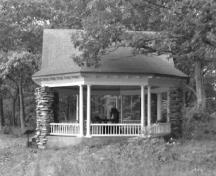 Side view of the Gordon Island Pavilion, showing the medium-pitched, octagonal roof structure supported by an articulated box beam, which in turn, is supported at the perimeter by slender paired wooden Doric columns, 1992.; Archeological Services and Historic Resources Ltd., 1992.