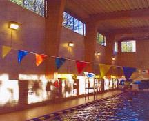 General view of the interior of the Swimming Pool RR22A showing the successful integration of traditional wood elements such as the glue laminated timbers with modern masonry elements such as the concrete surfaces and tile wainscoting, 2000.; Department of National Defence / Ministère de la Défense nationale, 2000.