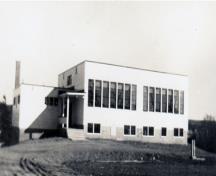 Cette image historique montre le bâtiment quand il a été utilisé comme l'école Cambridge Rural High School; Queens County Heritage Collection
