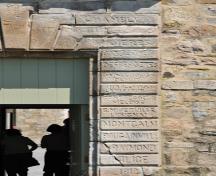 Détail du portail de l’entrée principale du fort Chambly agrémenté de maçonnerie rustique où sont inscrits les noms des personnages importants de l’histoire de la Nouvelle-France; Agence Parcs Canada | Parks Canada Agency