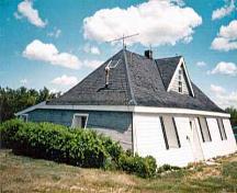 Vue générale de la maison de tourbe Addison, qui montre son contour au sol rectangulaire et sa volumétrie pyramidale d'un étage et demi, surmontée d'un toit à deux versants.; Parks Canada | Parcs Canada