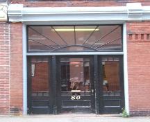 This image provides a view of the entry, with a transom window including fanned muntins over a wood door with a decorative glass panel, surrounded by side-lights, 2005.; City of Saint John