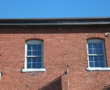 Andrew Malcolm's Warehouse - This photograph shows the 6 over 6  windows in segmented openings and roof-line cornice, 2005; City of Saint John