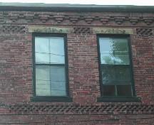 This image provides a view of the cornice ornamented with brick corbel bands, above the wood windows with decorative sandstone lintels and sills, 2005.; City of Saint John
