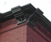 This image provides a view of the decorative wood brackets supporting the cornice that is ornamented by brick corbel bands, 2005.; City of Saint John