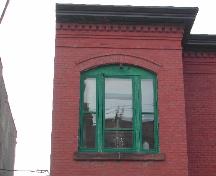 This photograph shows the cornice and one of the large segmented arch windows of the bay, 2005.; City of Saint John