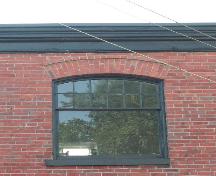 This image provides a view of the wood cornice with a segmented arch window below, 2005.; City of Saint John