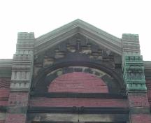 This photograph shows the gabled parapet that extends above the roof-line, and illustrates the brick work and layered brackets, 2005; City of Saint John