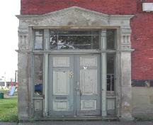 This photograph shows the entrance with sandstone pilasters and entablature, and illustrates the paired wooden door, sidelights and transom window, 2005; City of Saint John