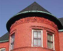 This photograph shows the conical roof of the tower, the decorative frieze band, the lintels and the protruding brick tracery, 2005; City of Saint John