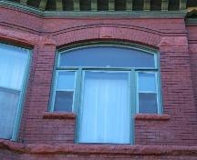 This photograph shows the segmented arch triple window and the continuous sills of the second storey, 2005; City of Saint John
