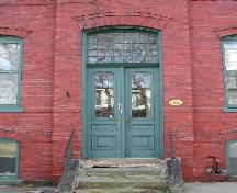 Cette photographie montre l'entrée de l'édifice avec l'imposte à panneaux de verre multiples et la porte en bois à panneaux de verre supérieurs, 2005; City of Saint John