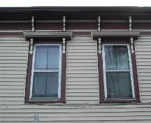 This photograph shows two windows with bracketed entablatures and the bracketed cornice, 2005; City of Saint John