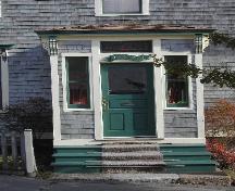 This photograph shows the porched entrance to the home, and illustrates the leaded glass transom window and brackets, 2005; City of Saint John