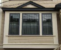 This image provides a view of one of the single storey bay windows crowned by a pediment and encasing tripartite window, 2005; City of Saint John