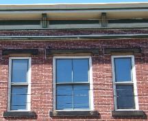 This photograph shows the roof-line cornice and the set of three windows, 2005; City of Saint John