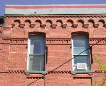 Cette photographie montre le bandeau d'arches en plein cintre aveugles à la ligne de toiture. Elle montre aussi les fenêtres et les assises de brique, 2007; City of Saint John