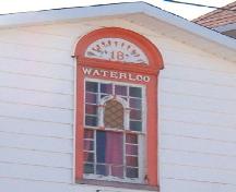 Exterior view of a coloured glass window on the main facade of Waterloo Loyal Orange Lodge No. 18, New Perlican, NL, Photo taken 2006. ; HFNL/Lara Maynard 2006