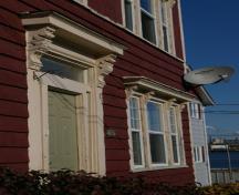 This image shows an angled view of the front door and main window with scrolled brackets under the entablatures; City of Saint John