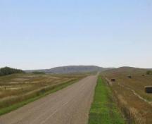 View of site location on distant hilltop, left of road, 2004.; Government of Saskatchewan, Marvin Thomas, 2004.