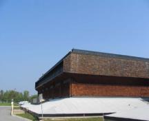 Vue de l'extérieur du bloc 1800, qui montre le parement en bardeaux de bois ainsi que la base pyramidale avec un toit en surplomb lourd en forme de boîte, 2005.; Parks Canada Agency / Agence Parcs Canada, Kate MacFarlane, 2005.