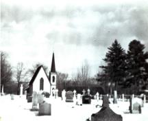This historic image from circa 1940 shows the cemetery with the church in the background; Queens County Heritage Collection