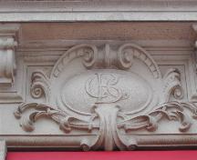 Ceci est un des huit emblèmes de CBC (la Banque canadienne de commerce) qui sont placés au-dessous des rebords qui sont situés sous les fenêtres du deuxième étage, 2004 
; City of Saint John