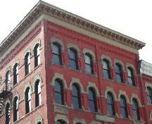 This photograph shows the heavily bracketed cornice and the Roman and pointed segmented arch windows, 2004; City of Saint John